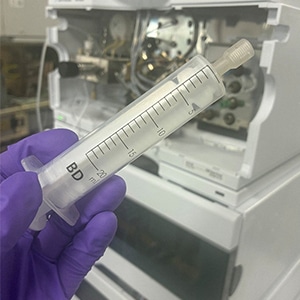 Large plastic syringe for priming solvent lines.